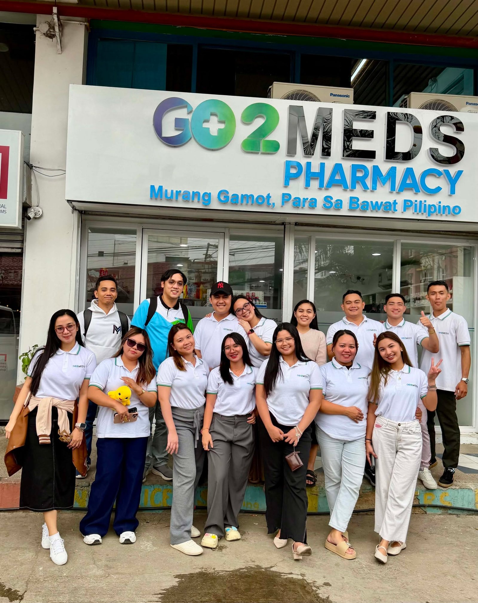 The Go2Meds Pharmacy team gathered in front of a branch storefront